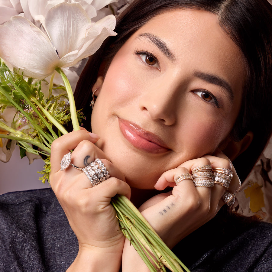 Dominique Cohen Shop the Look white gold diamond ultimate ring stacks on lovely young woman in front of white flowers; call 323-404-2959 for shop help